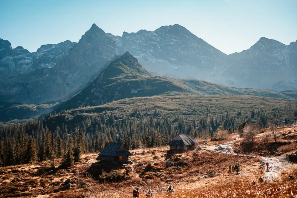Hala Gasienicowa z drewnianymi chatami gorskimi szlakiem turystycznym i wysokimi szczytami Tatr, Zakopane z dziećmi i wygodny nocleg dla rodzin planujacych wspolne wycieczki po Tatrach