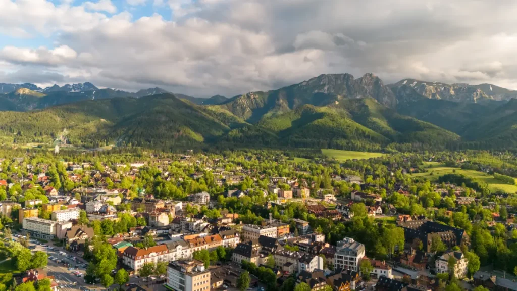 Panorama Zakopanego z lotu ptaka z widokiem na zabudowe miasta i pasmo Tatr, Zakopane z dziećmi i rodzinny nocleg zapewniajacy komfortowy wypoczynek blisko gorskich atrakcji