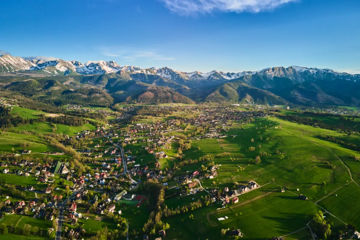Rozlegla panorama Podhala z zielonymi polami zabudowa i majestatycznymi Tatrami w tle, Rodzinny nocleg w Zakopanem w spokojnej okolicy idealnej na wypoczynek z dziecm
