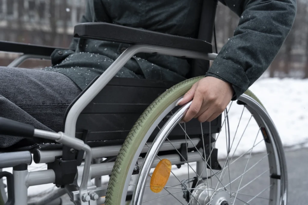Osoba poruszająca się na wózku inwalidzkim w zimowej scenerii, Dostępny nocleg w Zakopanem dla osób z niepełnosprawnościami i grup wymagających udogodnień